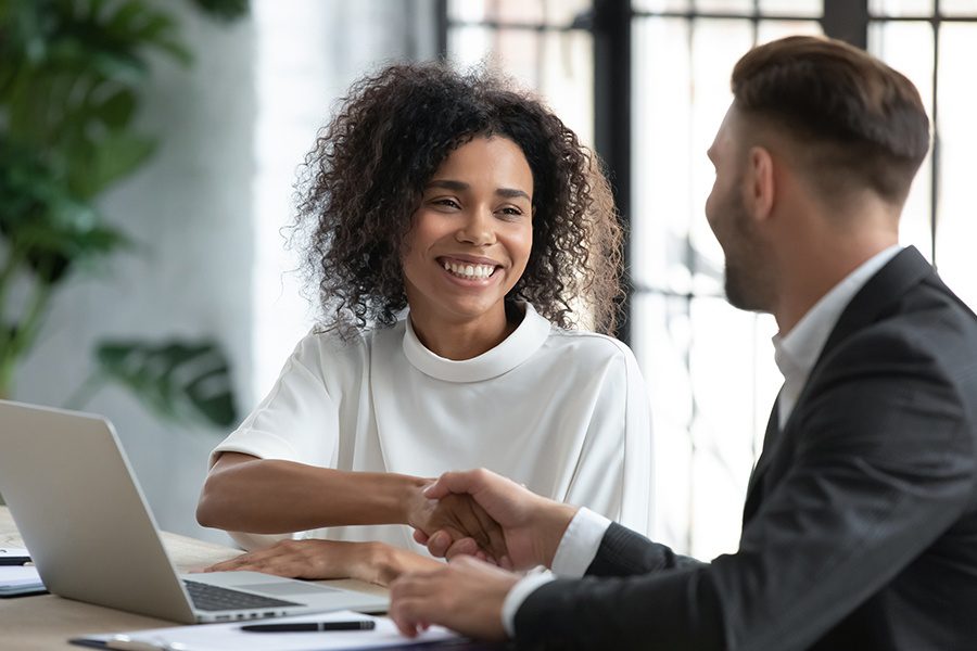 Investment Advisor Insurance - Smiling Woman Shaking Hands With Her Advisor at an Investment Meeting