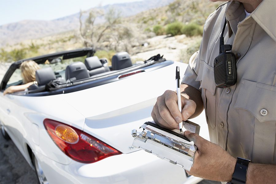 Constable Liability Insurance - View of a State Trooper Writing a Speeding Ticket for a Young Woman in a White Convertible