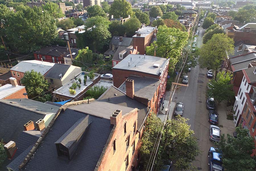 Contact - Aerial View of a Residential Neighborhood in Pittsburgh Pennsylvania with Green Trees and Parked Cars Along the Street