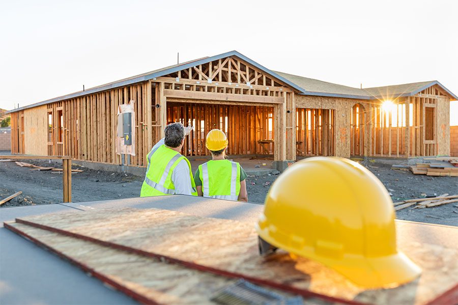 Contract Bonds - View of Two Contractors Standing on a Residential Jobsite Looking at a New Home Build