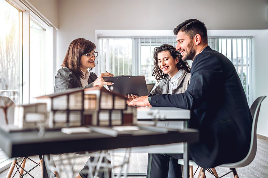 Mortgage License Bonds - View of a Cheerful Married Couple Signing Paperwork with a Mortgage Lender in the Office