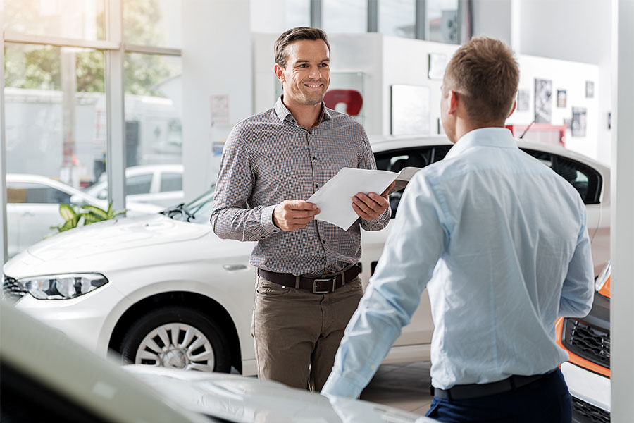 Pennsylvania Motor Vehicle Bonds - View of a Smiling Car Salesman Standing in a Car Showroom While Talking to a New Client