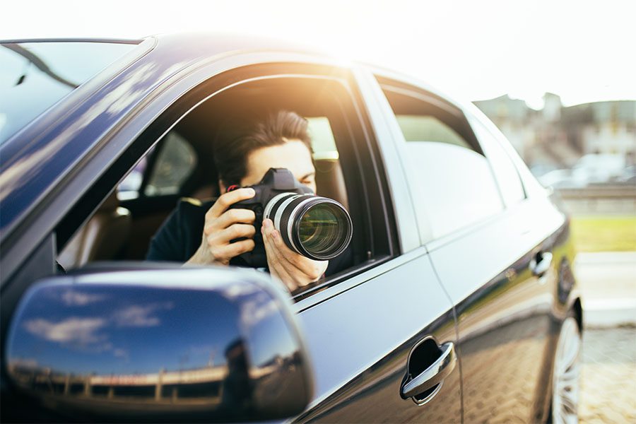 Private Investigator Insurance - View of a Private Investigator Sitting in a Car While Taking a Photo for a Client
