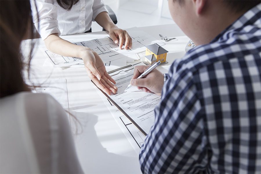 Title Agent Surety Bonds - Closeup View of a Married Couple Signing Paperwork with a Title Insurance Agent During Home Purchase